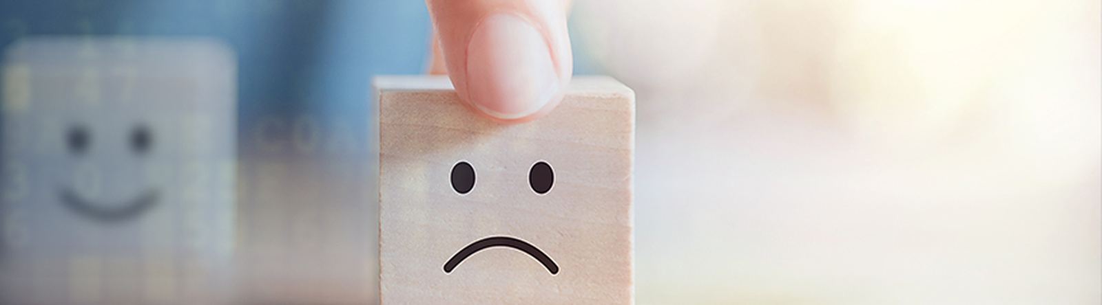 Happy and unhappy faces on wooden blocks