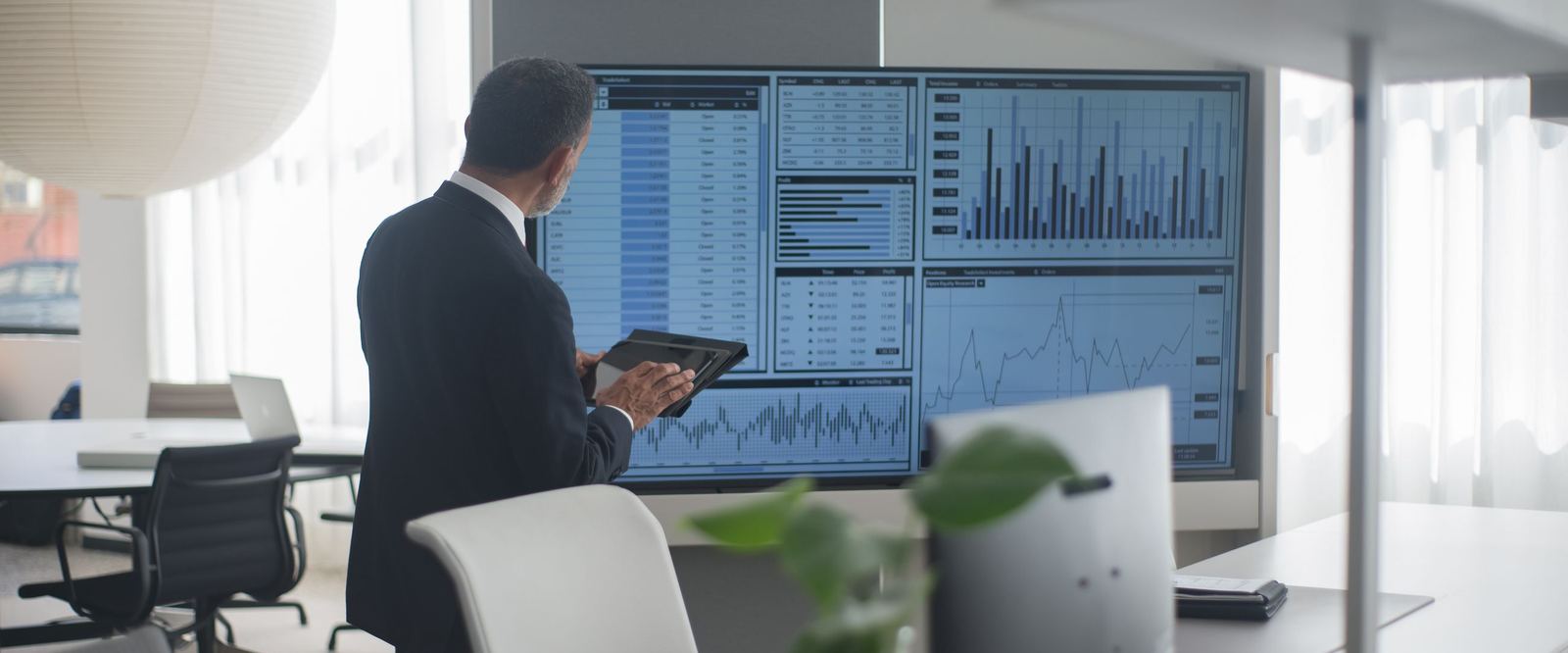 Executive reviewing scenario dashboards on a large screen